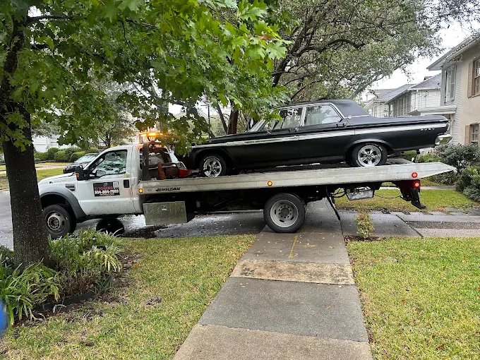 TJ Towing flatbed transporting a vehicle at sunset in New Orleans